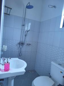 Un baño con inodoro, lavabo y ducha. en Tigris Residence, en Bulenga