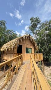 a wooden bridge leading to a hut with a thatch roof at Hotel Arara Azul in Aiparuça