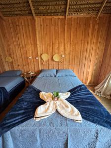 a bed with a blue comforter with a bow on it at Hotel Arara Azul in Aiparuça