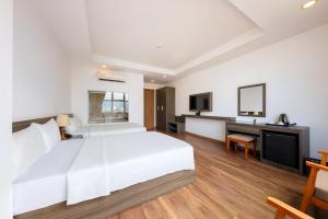 een slaapkamer met een groot wit bed en een bureau bij Dolphin Bay Hotel Nha Trang in Nha Trang