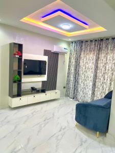 a living room with a tv and a blue couch at Fadaka Manor in Ibadan
