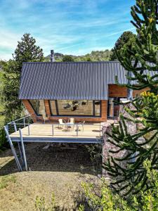 a house with a large wooden deck in the yard at Estrellas de la Laguna in Villa Pehuenia