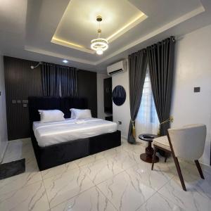 um quarto com uma cama grande e uma cadeira em Garnet Apartments em Iyiba