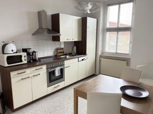a kitchen with white cabinets and a table and a microwave at Gästewohnung "Kleine Auszeit" in Halberstadt