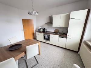 a kitchen with a wooden table and white cabinets at Gästewohnung "Kleine Auszeit" in Halberstadt