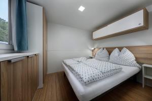 a bedroom with a white bed with pillows and a window at KNAUS Campingpark Nassau in Nassau +3 photos