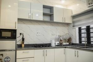 a kitchen with white cabinets and a stove top oven at 1 Bedroom - BFA Luxury Apartment Alagbaka Akure in Mama
