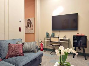 un soggiorno con un divano e una scrivania con una televisione di Cinisca Suite Rose a Bologna Altre 9 foto