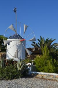 un molino de viento frente a una casa con palmeras en Anemomylos Houses, en Koufonisia