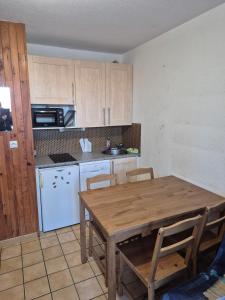 a kitchen with a wooden table and a white refrigerator at studio 4 couchages, pied des pistes in Risoul