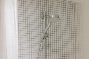 a shower head in front of a tiled wall at Copenhagen Studio Double Bed and Kitchen 3 in Copenhagen