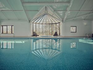 a swimming pool with two chairs and a large window at The Mole Resort - Lodges in Chittlehamholt
