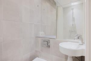 een witte badkamer met een wastafel en een spiegel bij Copenhagen Getaway Cute Studio for Two 7 in Kopenhagen