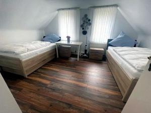 Dos camas en una habitación con suelo de madera y ventanas. en Bummelallee Schlösschen, en Bad Harzburg