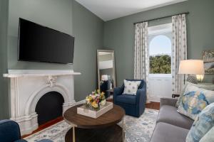 Una sala de estar con chimenea y televisión. en Hamilton Turner Inn, en Savannah