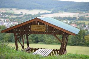 Ein Holzpavillon mit einem Schild auf einem Hügel in der Unterkunft Ferienwohnung Brama in Reinhardshagen