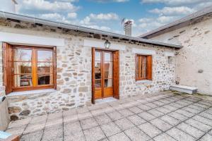 a stone building with a wooden door and windows at La grange du Petit Roure - A 20 km de Saint-Etienne in Grand Roure +5 photos
