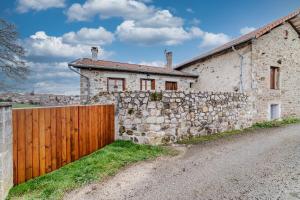 a stone house with a wooden gate and a stone wall at La grange du Petit Roure - A 20 km de Saint-Etienne in Grand Roure