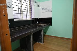 een badkamer met een zwart aanrecht en een wastafel bij Happy Homestay in Māvalli