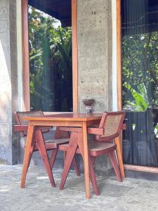 a wooden table and two chairs sitting next to a window at Balian River Hut in Balian