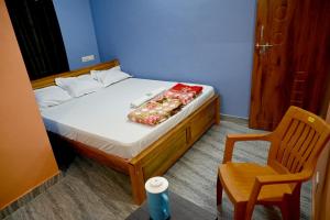 een kleine slaapkamer met een bed en een stoel bij Happy Homestay in Māvalli +3 foto's
