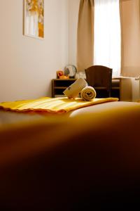 a bed with a yellow blanket and a book on it at London Rooms Zagreb Airport in Velika Gorica