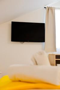 a flat screen tv hanging on a white wall at London Rooms Zagreb Airport in Velika Gorica +49 photos