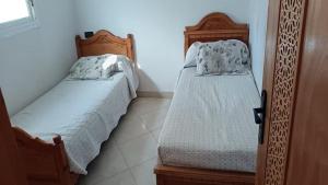 2 Betten in einem kleinen Zimmer mit einer gedankenlosen, gedankenlosen, gedankenlosen, gedankenlosen, gedankenlosen in der Unterkunft Petit appartement à martil in Martil