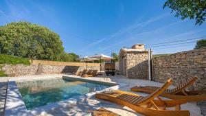 a swimming pool with two chairs and a stone wall at Holiday house Hedonica by Villas Guide in Mirlović Zagora