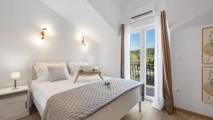 a white bedroom with a bed and a window at Holiday house Hedonica by Villas Guide in Mirlović Zagora +19 photos