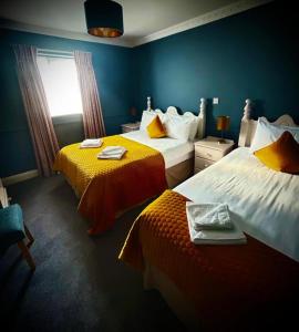 Una habitación de hotel con dos camas y una ventana. en The Royal Hotel, en Arklow