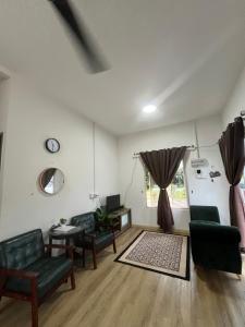 a living room with green furniture and a window at FMAZ Cottage in Kampong Gong