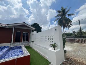 a house with a white fence and a palm tree at FMAZ Cottage in Kampong Gong