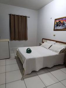 a bedroom with a bed with a green hat on it at Hotel Internacional in Cianorte