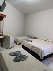 um quarto com três camas com chapéus em Hotel Internacional em Cianorte