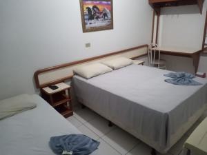 a room with two beds and a night stand at Hotel Internacional in Cianorte