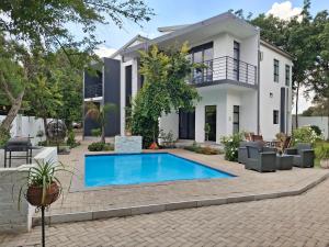 a villa with a swimming pool in front of a house at Bayley Boutique Guesthouse & Hydro Spa in Benoni