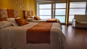 a hotel room with two beds and a chair at Hotel Casa Madrigal in Pasto