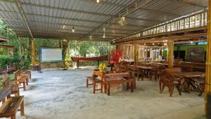 a restaurant with wooden tables and chairs and a screen at Baan Gamnan Resort Krabi in Ban Khao Ngam