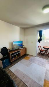 Una sala de estar con un televisor de pantalla plana y una mesa. en Mar Perto, Estilo e Conforto, en Ilha da Restinga