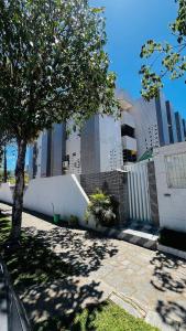 un árbol frente a un edificio con una valla en Mar Perto, Estilo e Conforto, en Ilha da Restinga