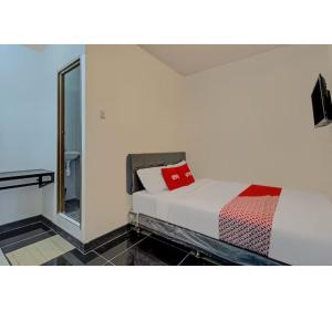 スラバヤにあるCapital O 3198 Sukomanunggal Innのベッドと鏡のある寝室