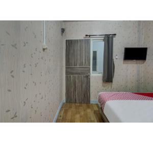 スラバヤにあるCapital O 3198 Sukomanunggal Innのベッドが2つと壁にテレビがある部屋