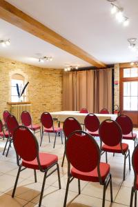 a conference room with red chairs and a table at Hôtel - Restaurant Au Tonnelier in Bergues