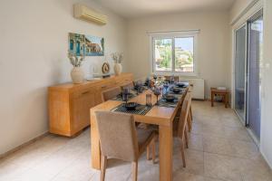 Seaview Villa Selenia pool & jacuzzi in Neo Chorio في نيو تشوريو: غرفة طعام مع طاولة خشبية مع كراسي