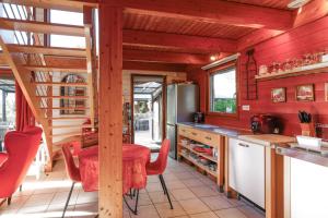 a kitchen with red walls and a table with red chairs at L'écrin de bois -sauna - spa in Mur-de-Bretagne