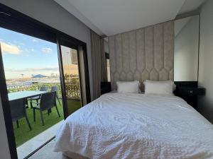Un dormitorio con una cama y un balcón con una mesa. en Marina Smir Port Luxury 2BR - Seaview - Beachfront, en Marina Smir