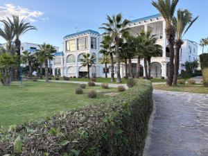 Un gran edificio blanco con palmeras delante. en Marina Smir Port Luxury 2BR - Seaview - Beachfront, en Marina Smir