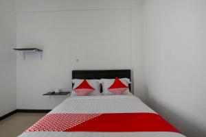 a bedroom with a bed with red and white pillows at Hotel O Forrest’inn in Kediri