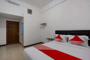 a bedroom with a bed with red and white pillows at Hotel O Forrest’inn in Kediri